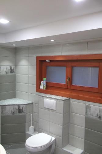 a white bathroom with a toilet and a sink at Szilvia Vendégház in Izvoare