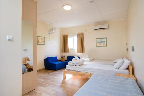 Habitación con 2 camas y sofá azul en Kibbutz Inbar Country Lodging, en Kibbutz Inbar
