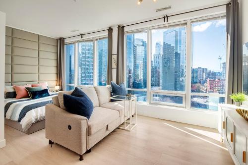 a bedroom with a couch and a bed and windows at City Centre Studio - Best Location! in Vancouver