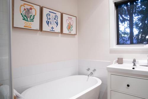 a white bathroom with a tub and three pictures on the wall at Clara Luce` in Bright