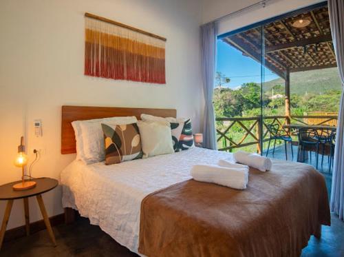 a bedroom with a bed with a view of a balcony at Chalé Lar do Capão in Vale do Capao
