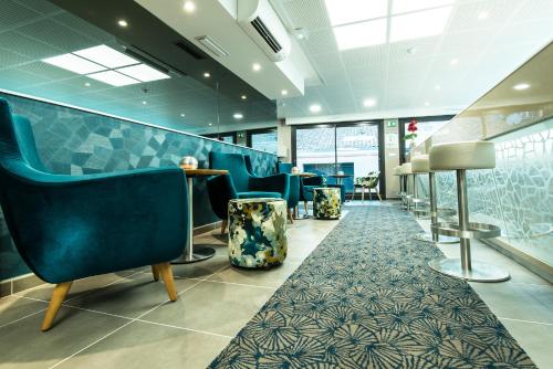 a waiting room with blue chairs and a carpet at Unique Hôtel Résidence & Spa in Saint-Raphaël