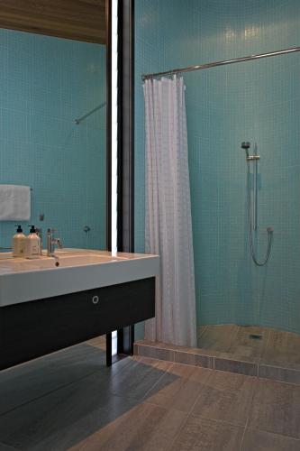 a bathroom with a tub and a shower with a sink at Hot Water Beach Bure Wera in Hotwater Beach