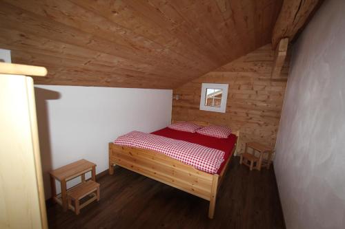 a small bedroom with a red bed in a wooden room at Chalet Daheim in Reckingen - Gluringen