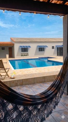 a hammock in front of a swimming pool at Casa Espaçosa com Piscina, 4 Quartos e Ar-Condicionado in Itanhaém