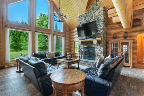 a living room with leather furniture and a stone fireplace at Fiddler Lake Resort - Moose 46 in Mille-Isles