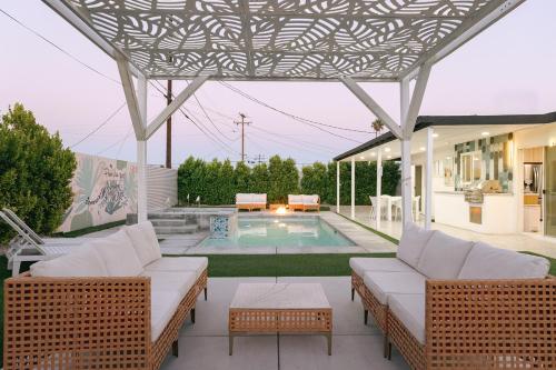 a patio with wicker furniture and a swimming pool at Palm Vista by Rather Be Properties in Palm Springs
