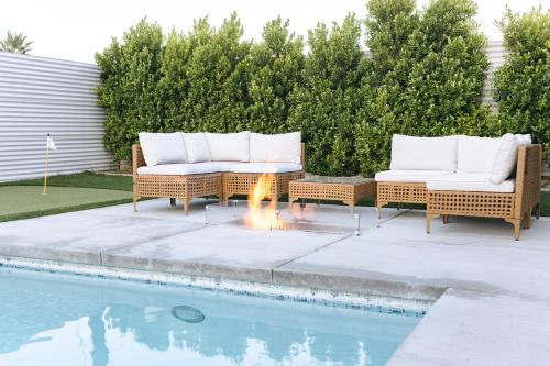 two wicker chairs and a fire pit next to a pool at Palm Vista by Rather Be Properties in Palm Springs