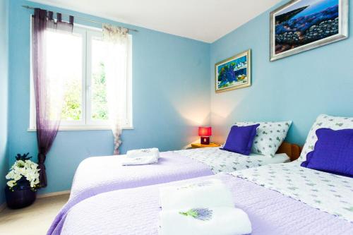 a blue bedroom with two beds and a window at Holiday Home Villa Pindo in Ston