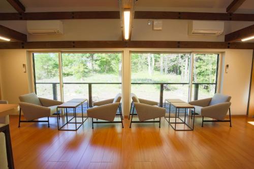 a room with chairs and tables and large windows at 森のオフィス Living in Fujimi