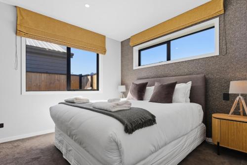 a bedroom with a large white bed with windows at The Reserve on Wooing Tree in Cromwell