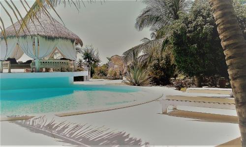 a swimming pool with a bench and palm trees at Lady D House in Watamu