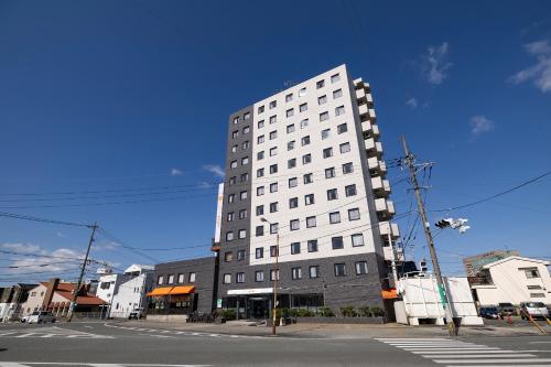 a tall white building on the corner of a street at KOKO STAY Kumamoto Yatsushiro - formerly Hotel Wing International Kumamoto Yatsushiro in Yatsushiro