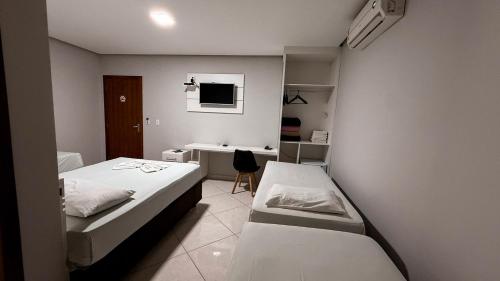 a small room with two beds and a desk at Hotel Estrela de Minas in São Gabriel