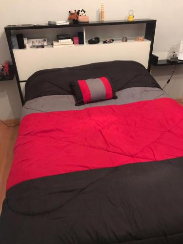a large bed with a red and black comforter at NM Apartamentos - LANUS OESTE in Villa Sarmiento