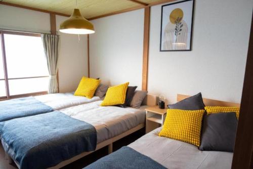 a room with three beds with yellow and blue at Biei Relax Stay B in Biei