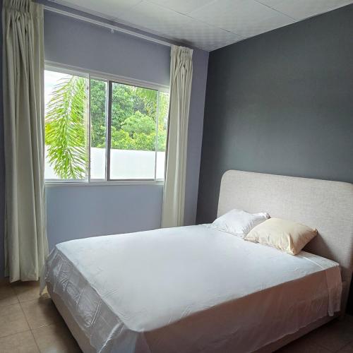 a bed in a bedroom with a large window at Oasis House 1 in Cabuya