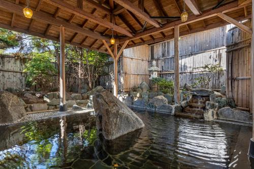 a pool of water in a building with a large rock at Kamenoi Hotel Tsukubasan in Tsukuba