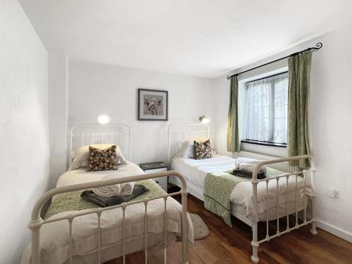 a bedroom with two beds and a window at Stables Cottage Ellicombe in Minehead