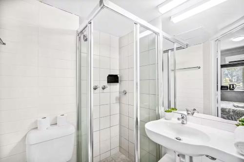 a white bathroom with a shower and a sink at Darwin CBD Escape-Cosy and Central in Darwin