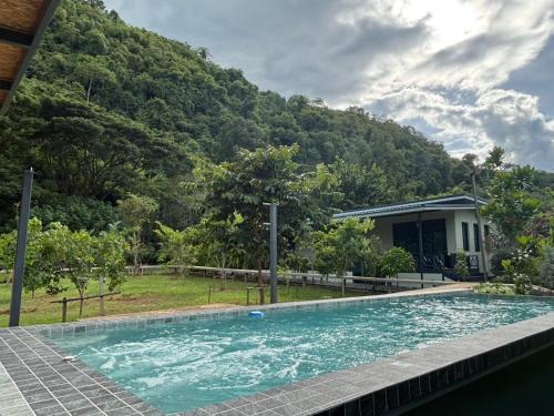 a swimming pool in front of a house with a mountain at The O' Khao Yai Mountain View Pool & Sauna Villa in Ban Tha Chang