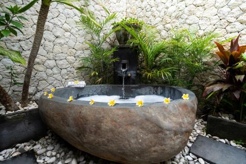 a stone tub with a fountain in a garden at Fraser Baye Villas in Uluwatu