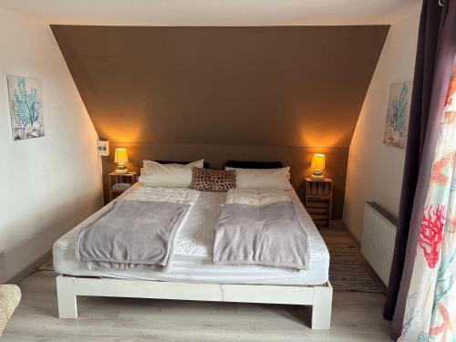 a bedroom with a large white bed with two lamps at Golfhues-Simone-Ferienwohnung-Suedbalkon in Wulfen auf Fehmarn
