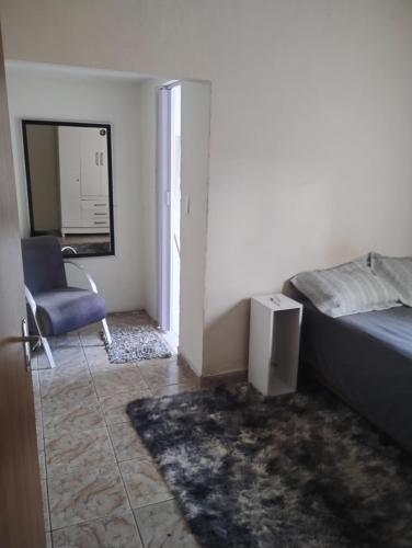a bedroom with a bed and a chair and a mirror at Quarto casal com banheiro in Sao Jose do Rio Preto