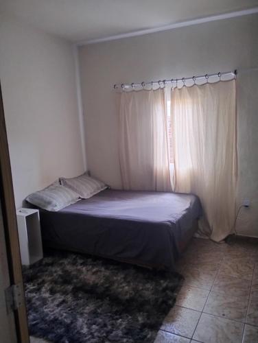 a small bedroom with a bed and a window at Quarto casal com banheiro in Sao Jose do Rio Preto