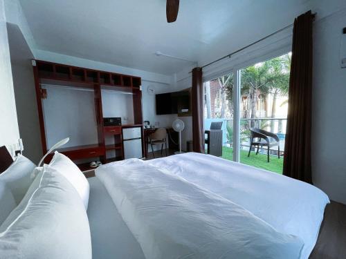 a bedroom with a large white bed and a window at Montani Beach Resort Puerto Galera powered by Cocotel in Puerto Galera