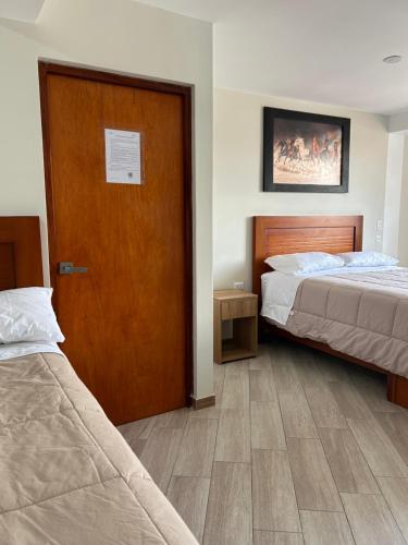 a room with two beds and a wooden door at Hotel Altavista in Abancay