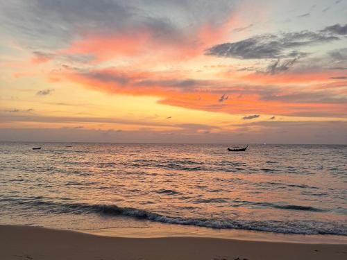 a sunset on the beach with a boat in the water at Pearl of Naithon beach 4 Bedrooms in Phuket