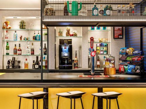 a bar with three stools in front of a counter at ibis London Greenwich in London