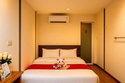 a bed with a teddy bear sitting on top of it at innbox Chiangmai Hotel in Ban Si Ngam