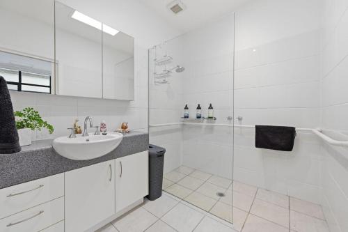 a white bathroom with a sink and a shower at Tide & Town - Perfectly Located! in Inverloch