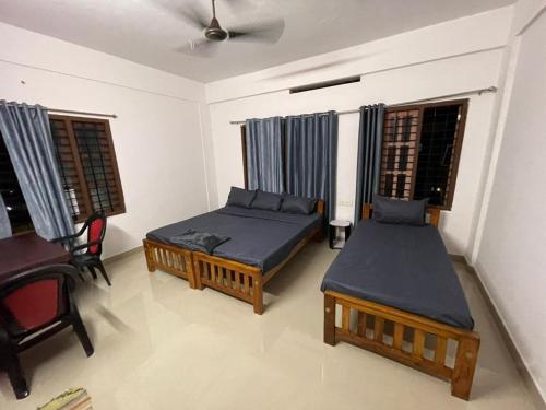 a room with two beds and a chair and windows at Southern Cliff House in Varkala