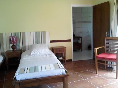 1 dormitorio con 1 cama y 1 silla roja en Gîte Domaine de la Ferme d'Erambere lot 67 route de la Nondoue, en Dumbéa