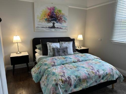 a bedroom with a bed and two lamps and a tree at Daisy Cottage on Duke 3BR in Yarram