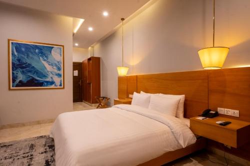 a bedroom with a large white bed and two lights at Hotel One Gujranwala in Kot Mergulla