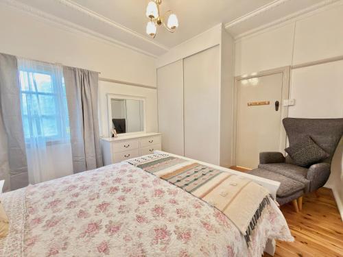 a bedroom with a bed and a chair and a window at 72 Cobra Street House in Dubbo