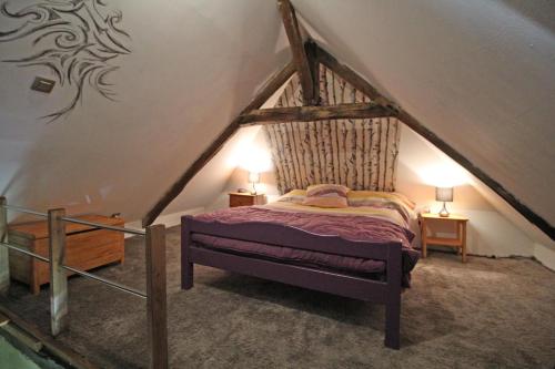 a bedroom with a bed in the attic at Les pierres du mas in La Porcherie