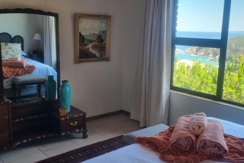 a bedroom with a bed with a mirror and a window at Fynbos & Foam in Herolds Bay