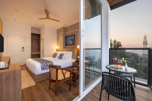 a hotel room with a bed and a table with a glass door at Hotel Mountain Mirage in KumhÄrsain