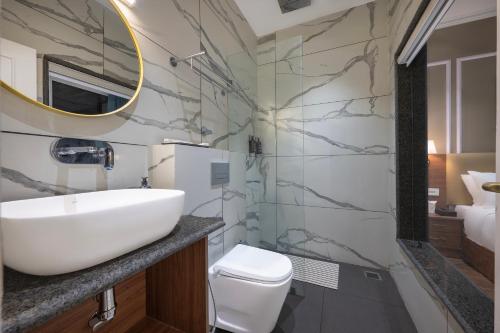 a bathroom with a sink and a toilet and a mirror at Hotel Mountain Mirage in KumhÄrsain