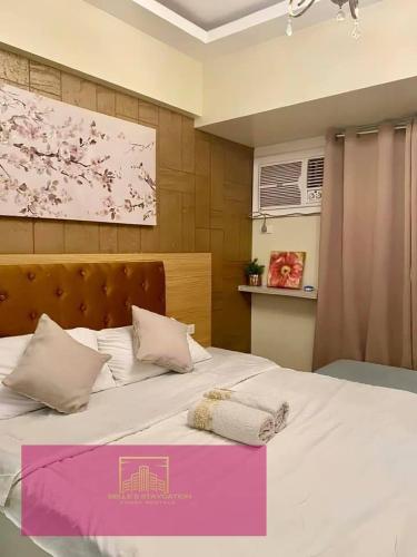 a bedroom with a large white bed with pink accents at Janeeka's Airie Avida Riala Cebu in Cebu City