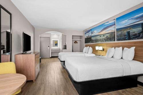 a hotel room with two beds and a flat screen tv at Days Inn by Wyndham Dallas Plano in Plano