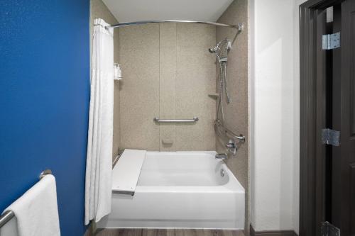 a bathroom with a shower and a white bath tub at La Quinta by Wyndham Kyle - Austin South in Kyle