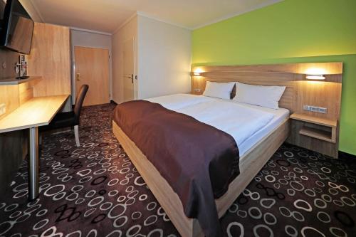 una camera d'albergo con un grande letto e una scrivania di Hotel sleep & go a Bad Hersfeld