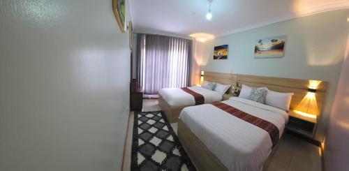 a hotel room with two beds and a window at Cafe La Vida in Mbarara
