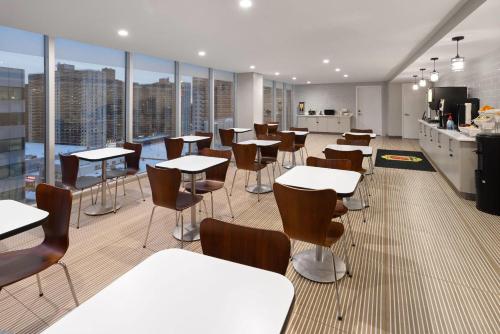 a dining room with tables and chairs and windows at Super 8 by Wyndham Bronx Near Stadium in Bronx